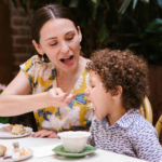 Mom is feeding the child at a table outside.