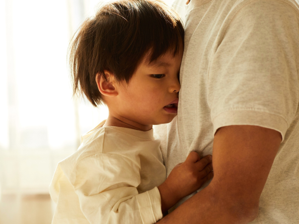 A young child is not feeling well and is being held by his dad.